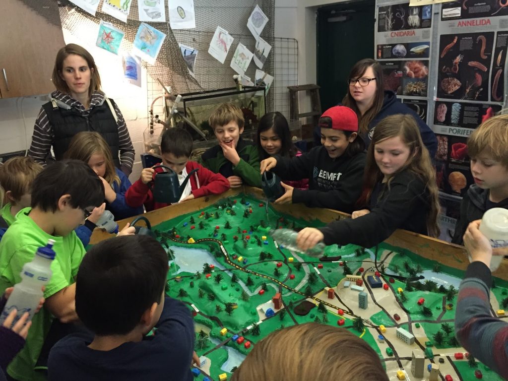 Children gathered around the watershed model of the Gorge Waterway